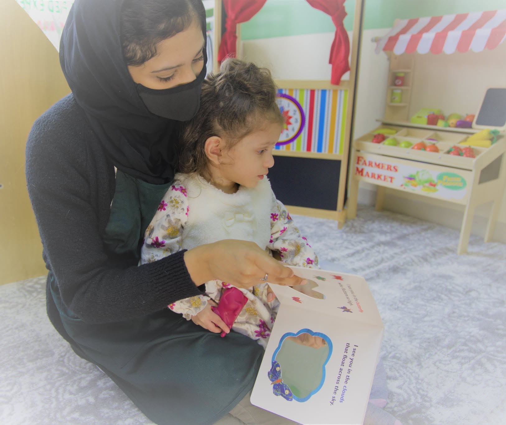 Teacher reading a book with children at Little Muslims