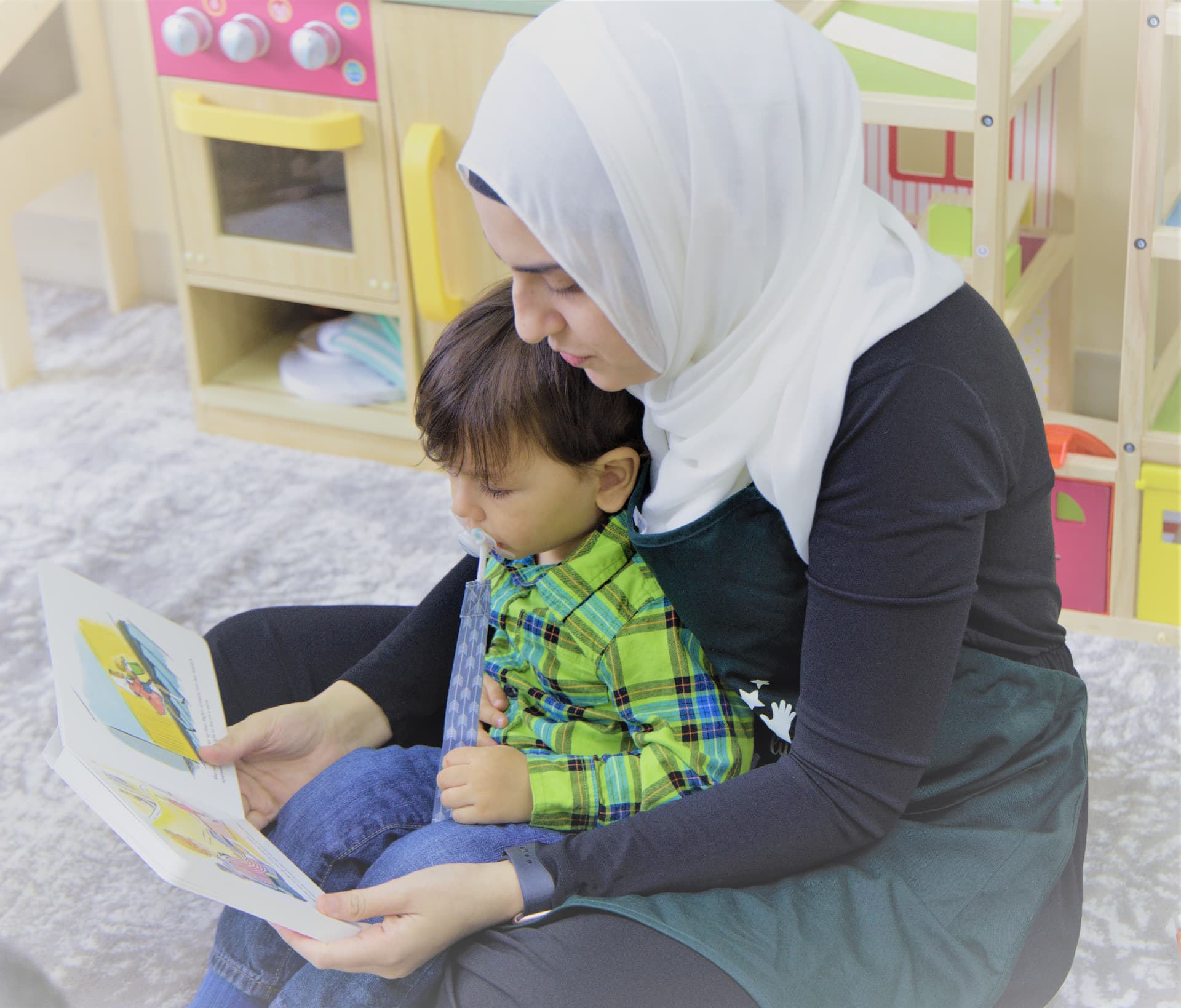 Teacher reading a picture book with a toddler on her lap