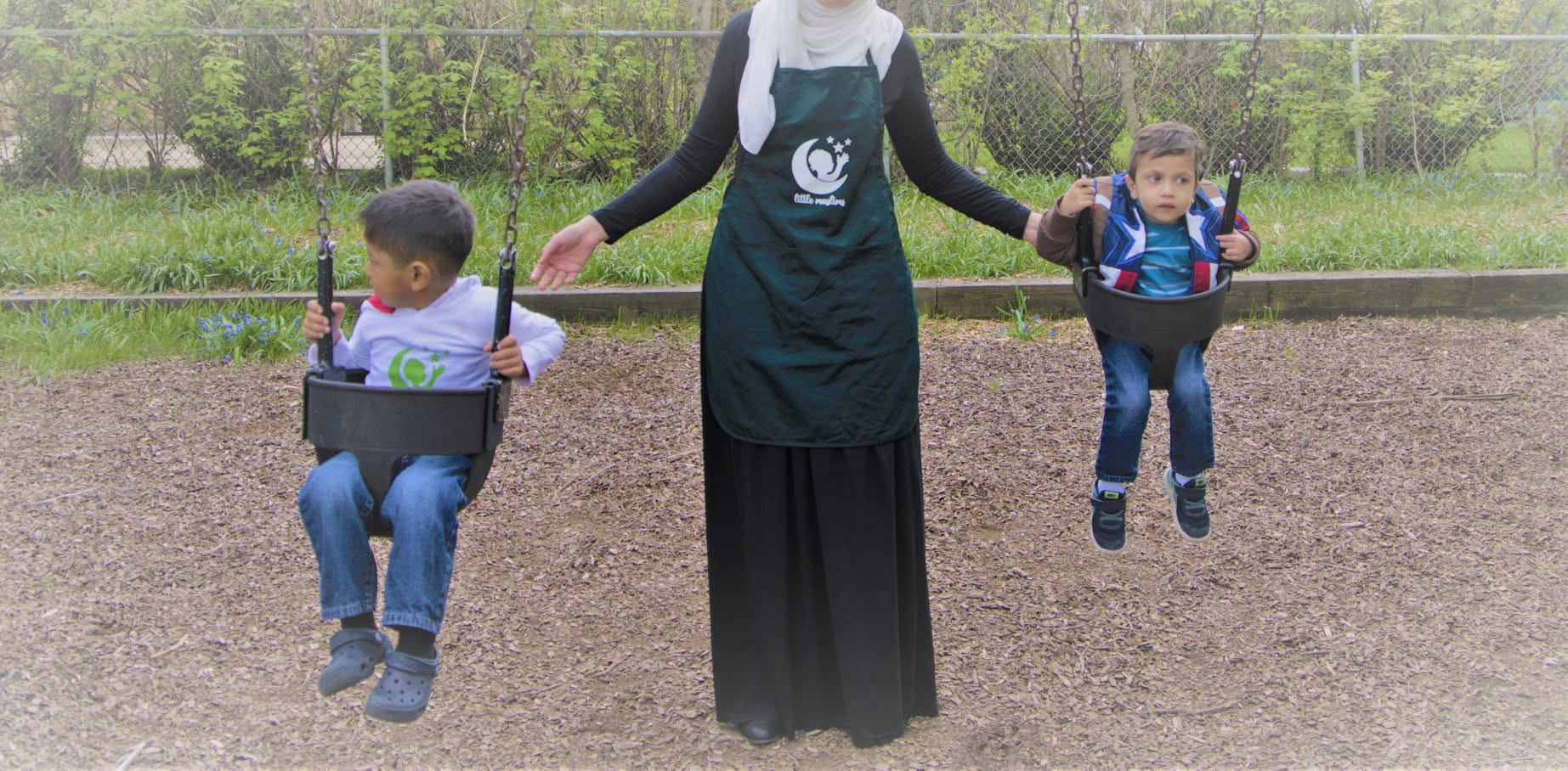 Teacher pushing children on swings outdoors